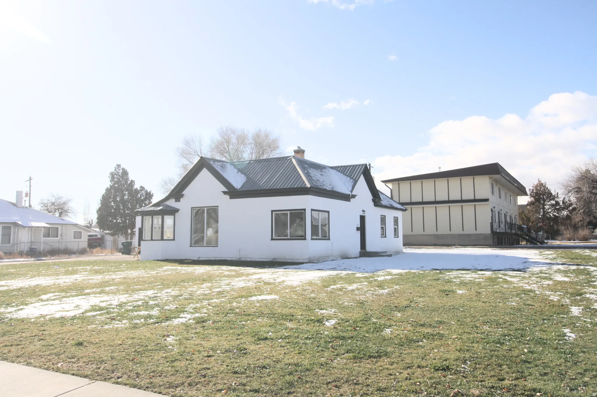 View of front of house with a chimney, a lawn, and stucco siding