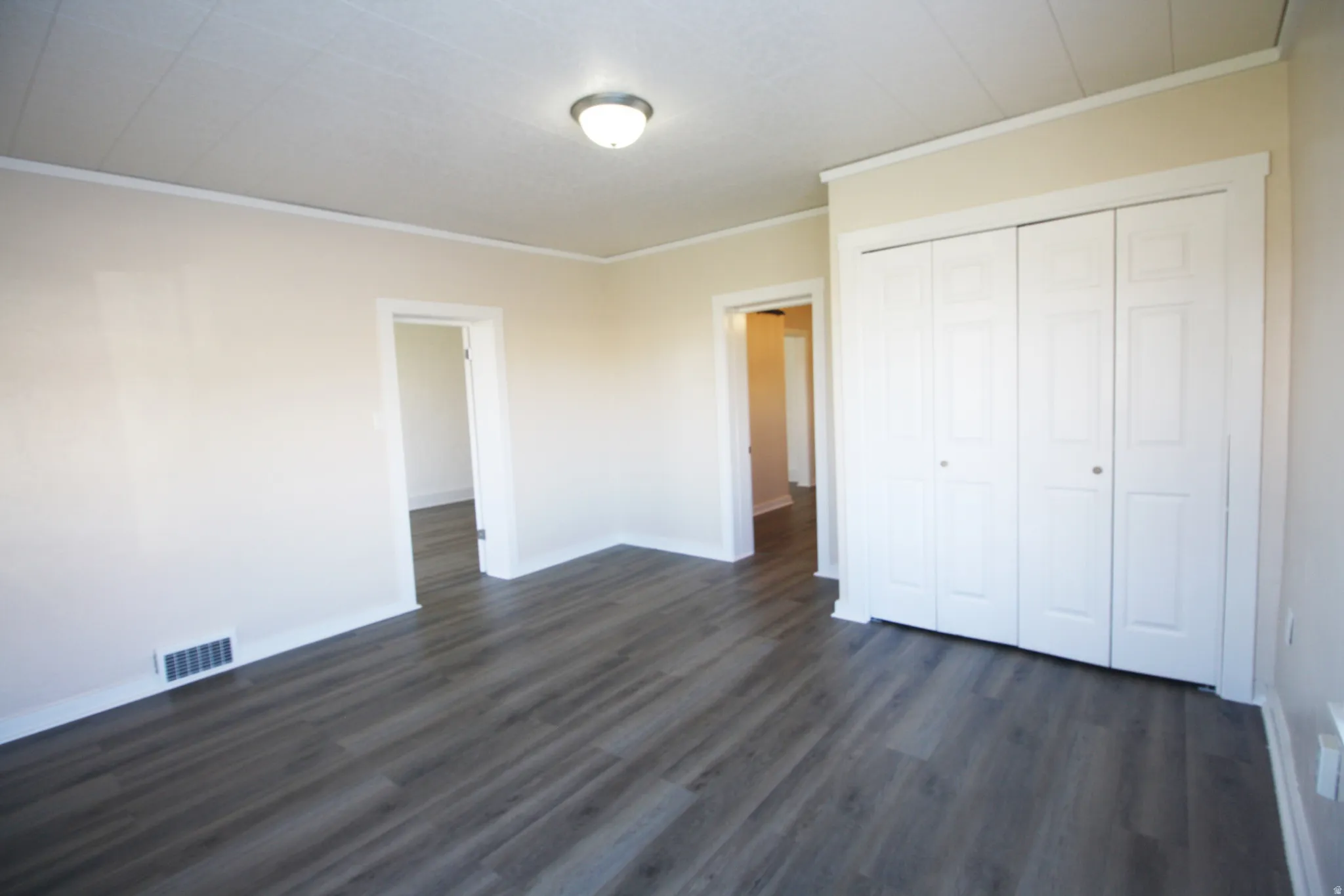 Bedroom 2 featuring crown molding, dark wood-style flooring, and a closet