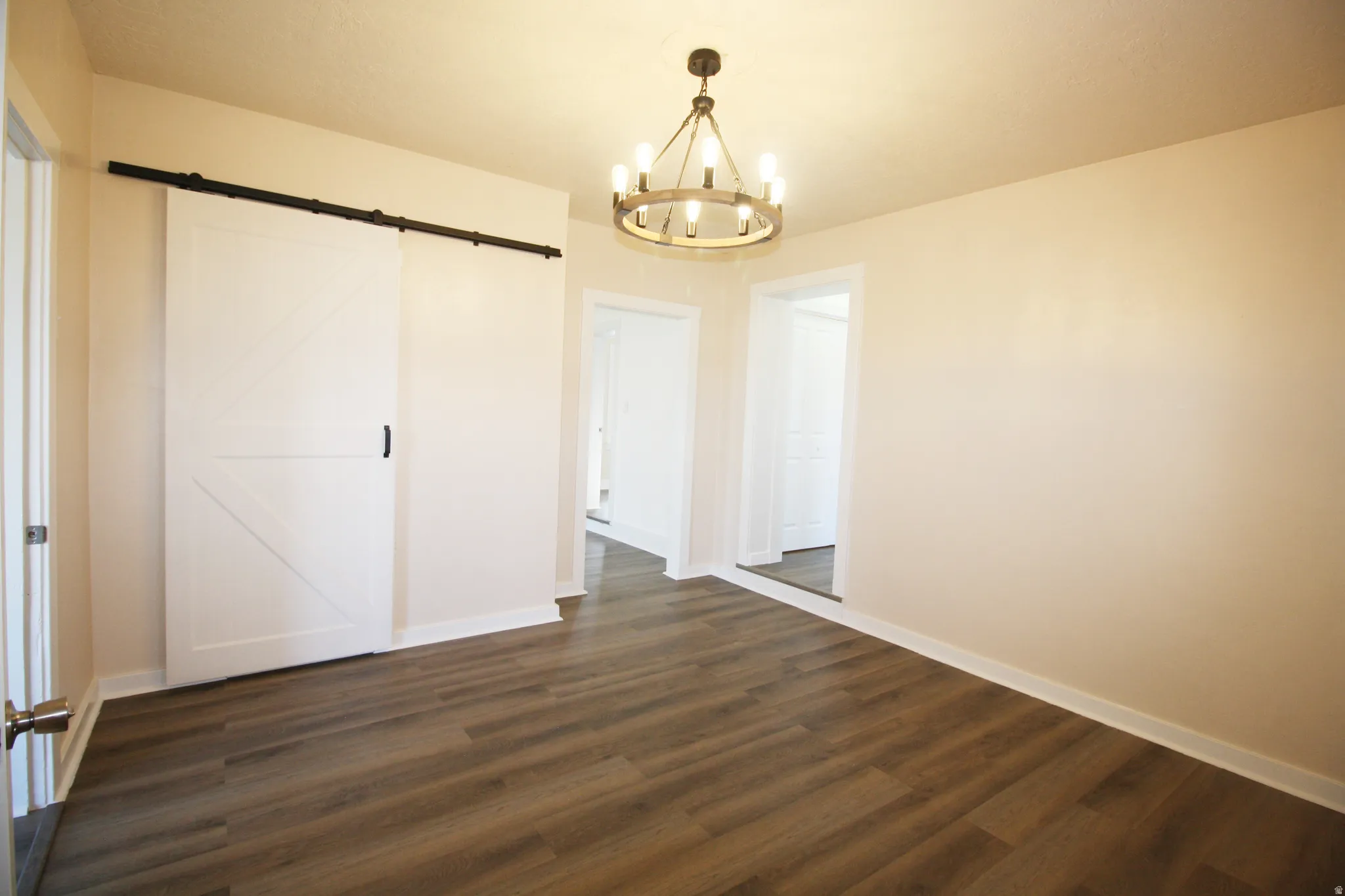 Formal Living area with a barn door, a chandelier, and dark wood-style floors