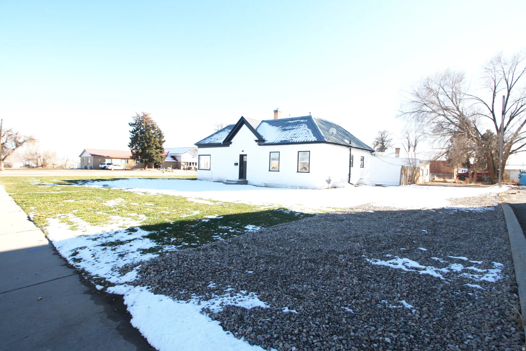 View of snow covered exterior featuring a yard, stucco siding, and a chimney