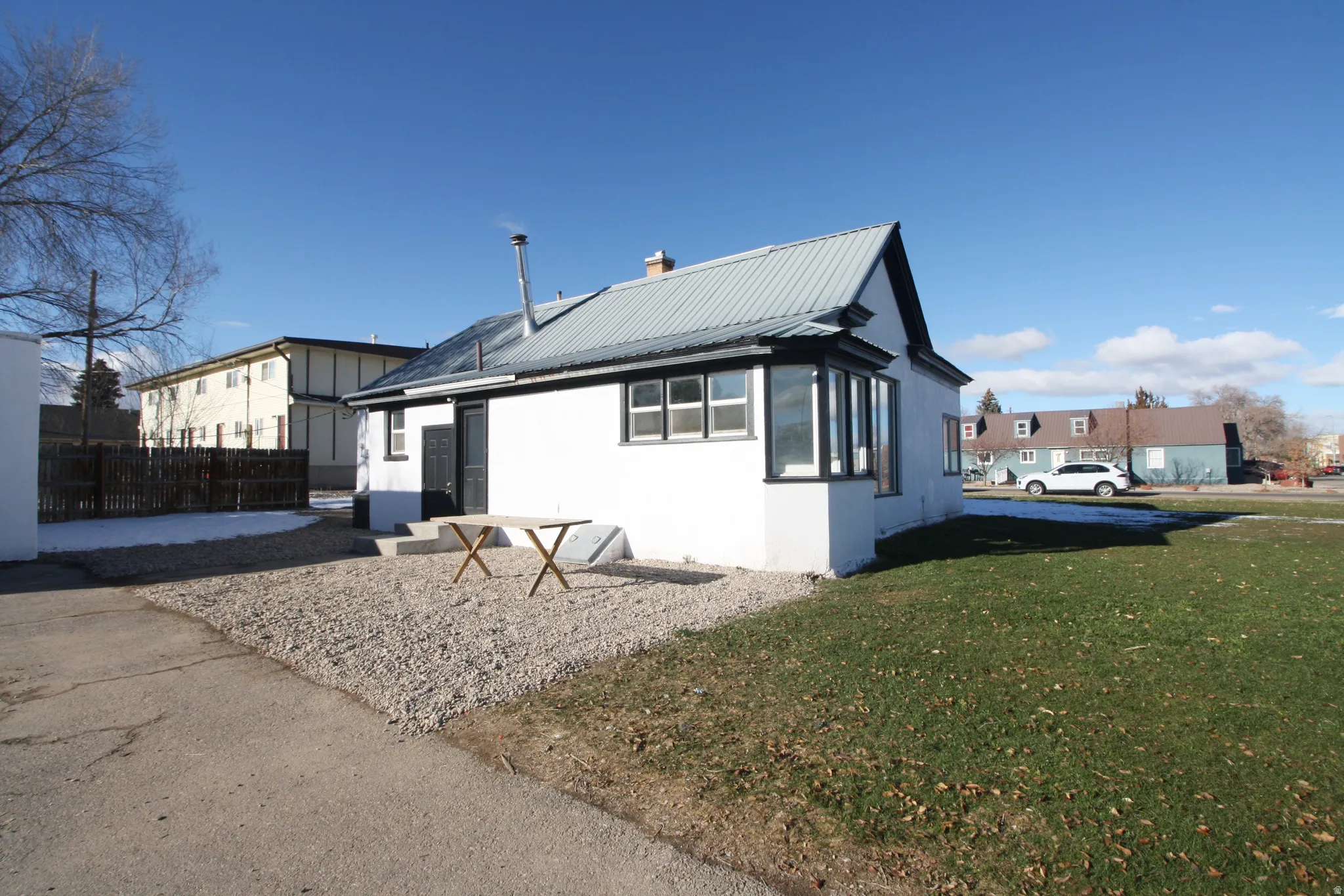 View of front of house with a metal roof, stucco siding, a chimney, and a front lawn