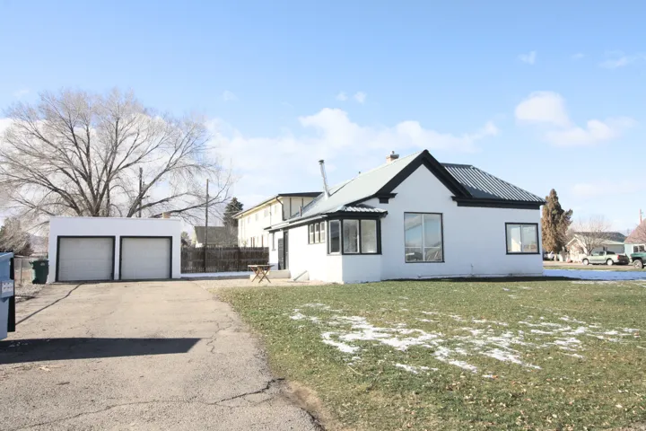 View of side of home with a metal roof, an outbuilding, a garage, a lawn, and stucco siding