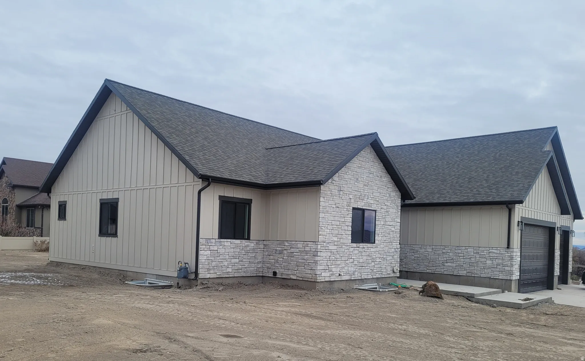 View of front of property featuring stone siding, roof with shingles, and board and batten siding