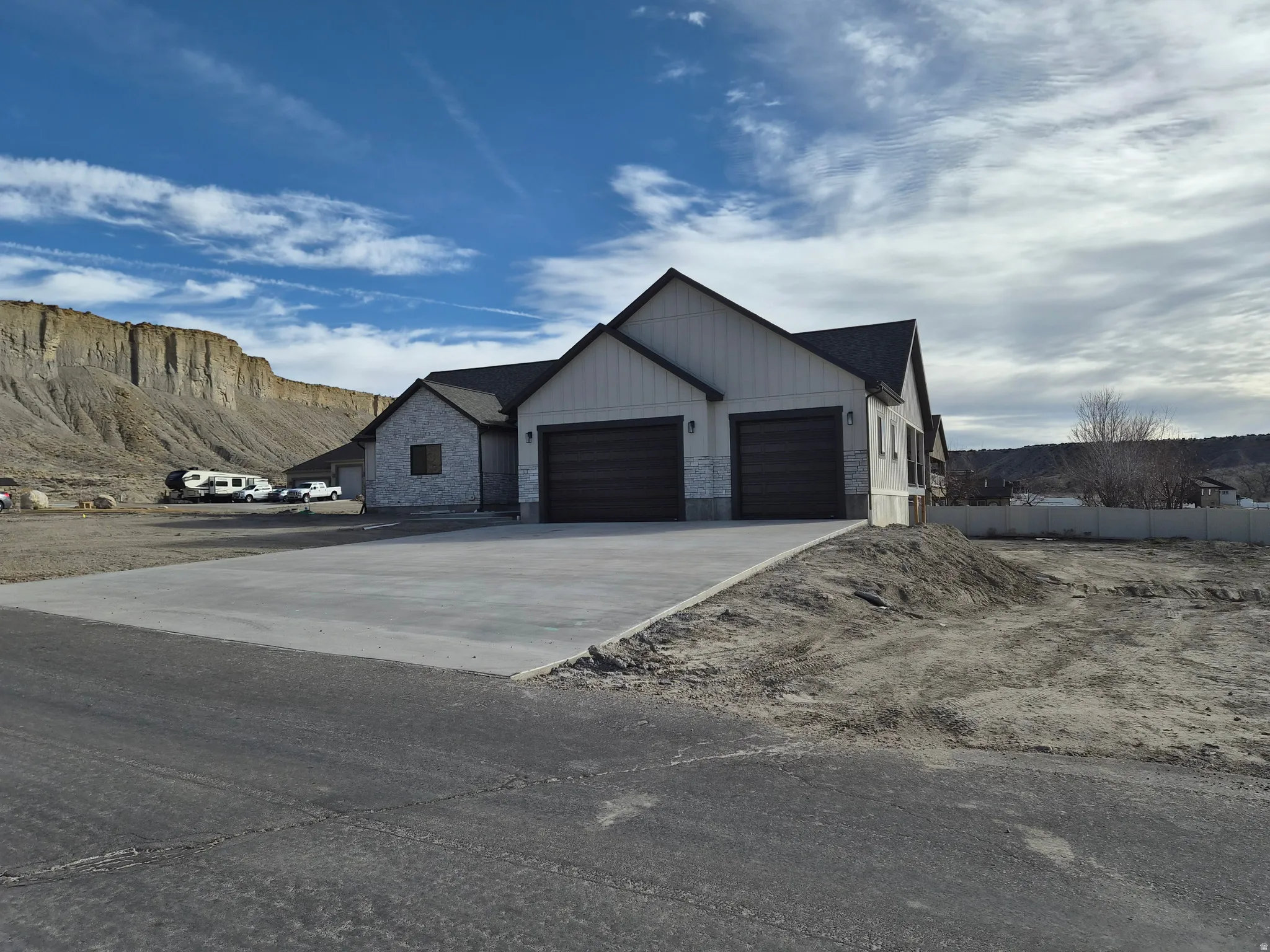 Modern inspired farmhouse with a garage, stone siding, concrete driveway, and a mountain view