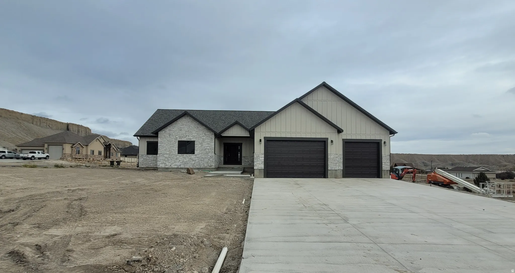 View of front of house featuring stone siding, board and batten siding, driveway, an attached garage, and a shingled roof