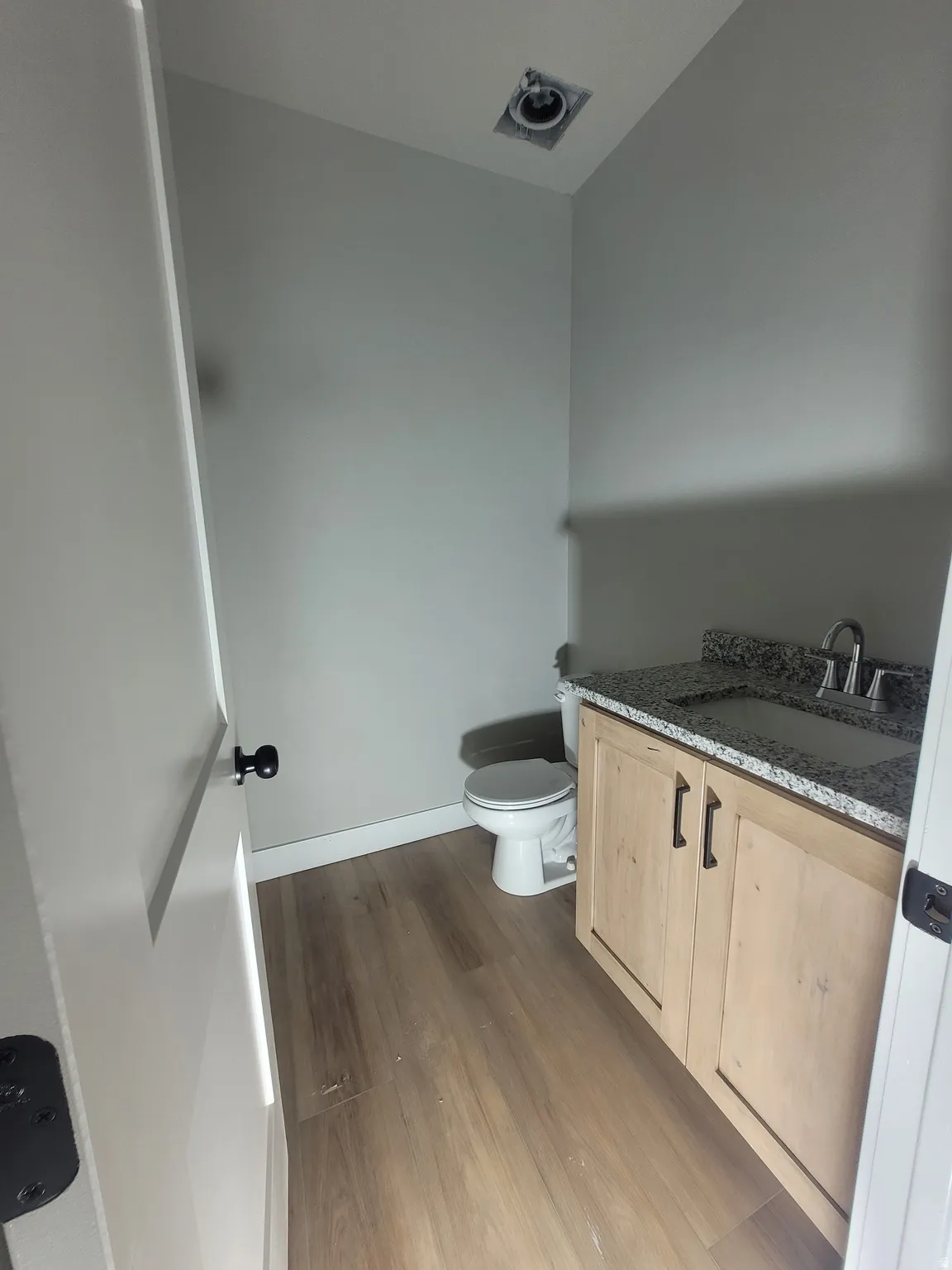 Half bathroom featuring vanity and dark wood-style floors