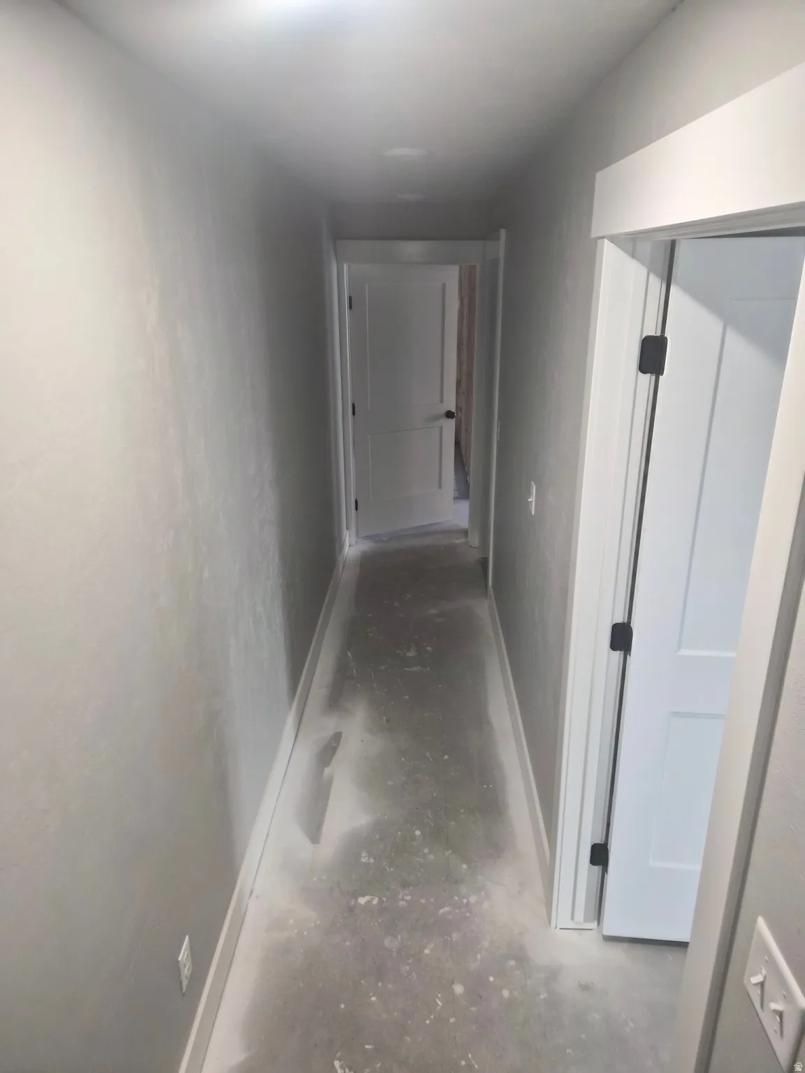 Hallway featuring unfinished concrete flooring and baseboards