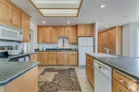 Kitchen with dark countertops, white appliances, and recessed lighting