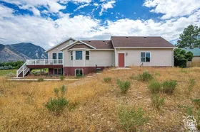 Rear view of house featuring a deck with mountain view, stairway, and stucco siding