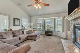 Living room with carpet floors, a fireplace, lofted ceiling, and a ceiling fan