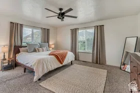 Bedroom with light carpet, multiple windows, and a ceiling fan