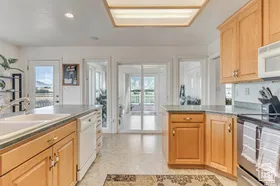 Kitchen with a peninsula, plenty of natural light, white appliances, recessed lighting, and light brown cabinetry