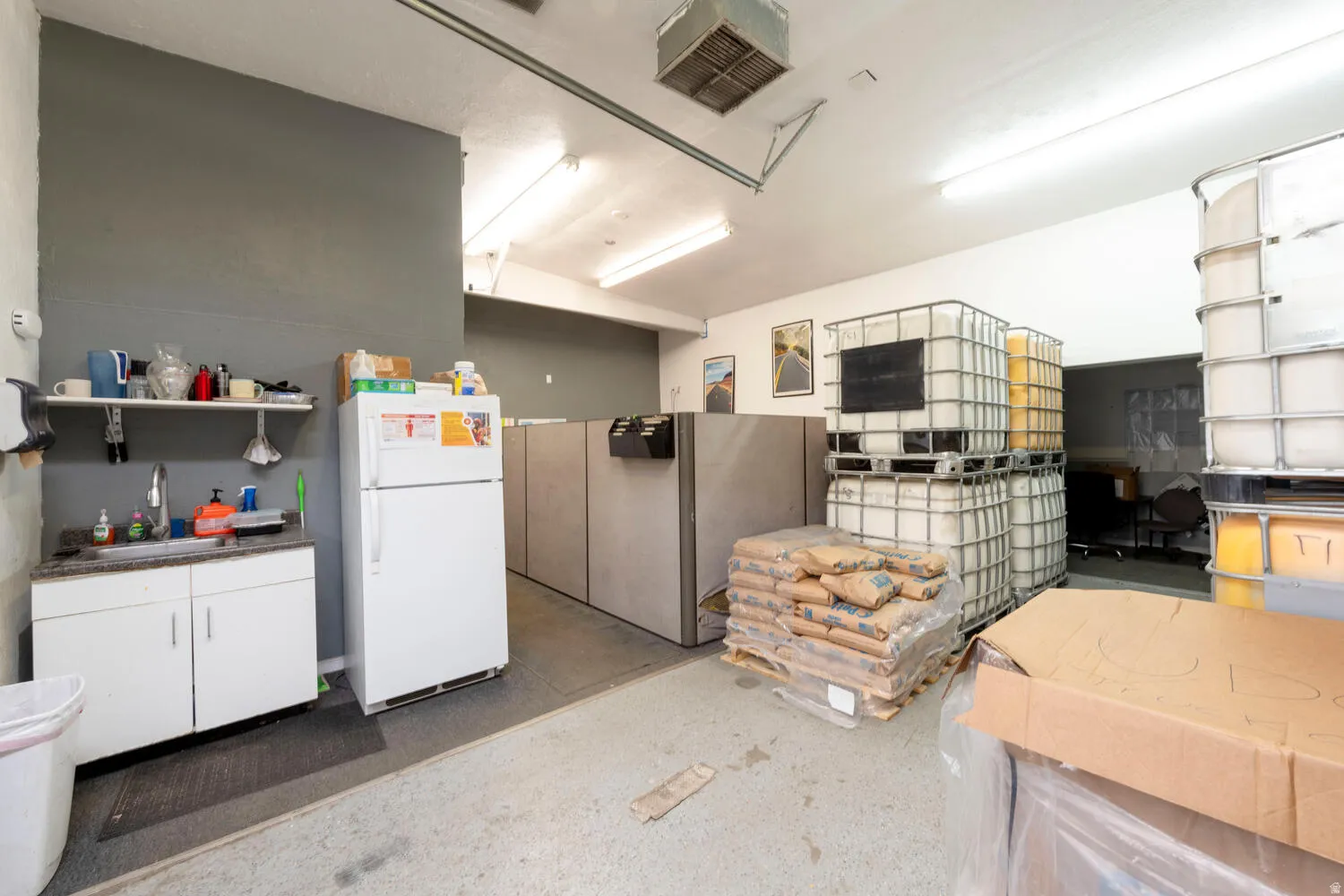 Misc room with a desk, a garage, and concrete flooring
