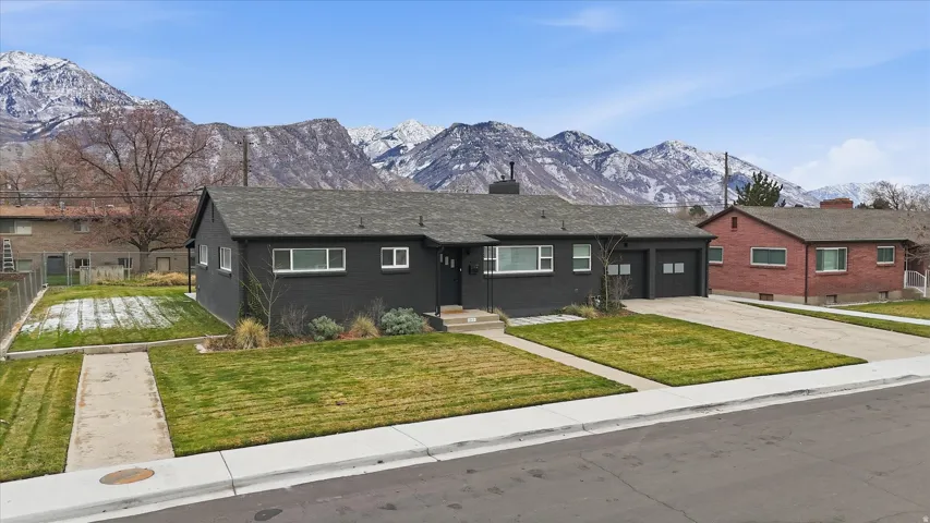 Single story home with driveway, a mountain view, a chimney, and brick siding