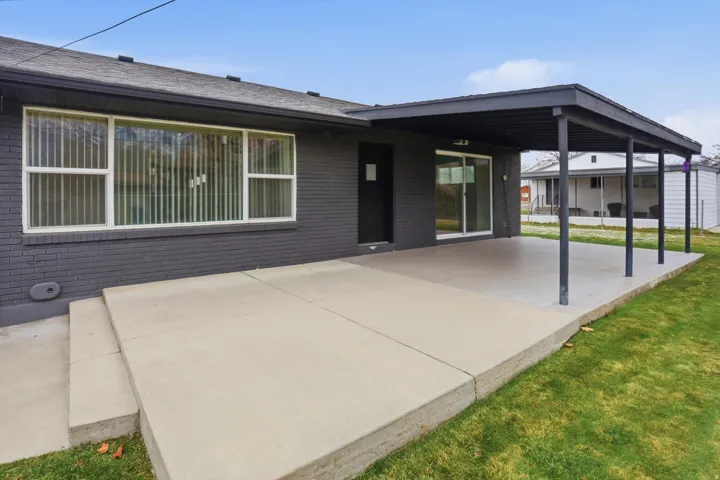 Back of house featuring brick siding, a patio area, and a yard