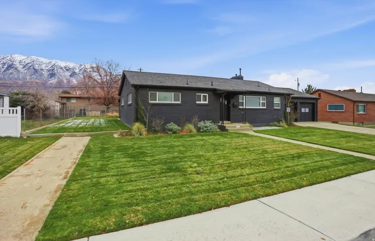 View of front of home featuring driveway, brick siding, a mountain view, and a chimney