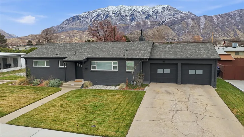 View of front of property with roof with shingles, a mountain view, concrete driveway, and brick siding