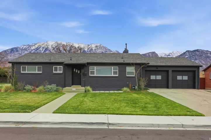 Ranch-style home featuring a mountain view, a front yard, an attached garage, and brick siding