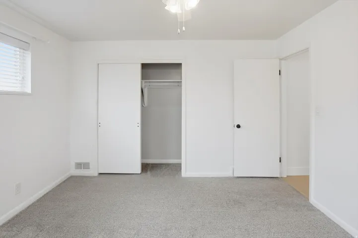 Unfurnished bedroom with light carpet and a closet