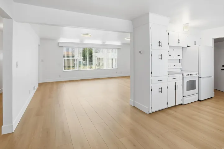 Kitchen with white appliances, white cabinetry, light countertops, and light wood finished floors