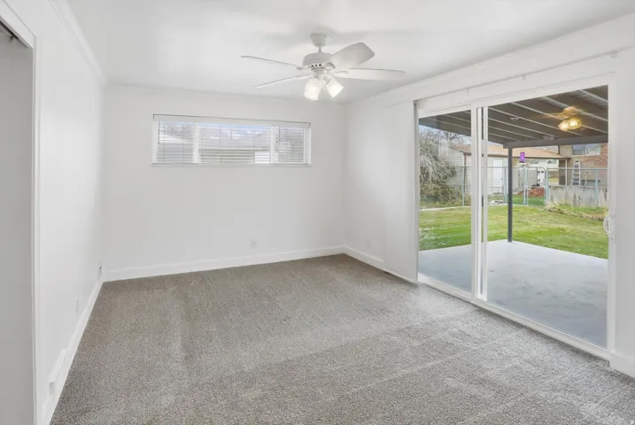 Unfurnished room with light carpet, plenty of natural light, a ceiling fan, and ornamental molding
