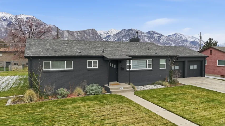 View of front of home with a mountain view, concrete driveway, a front yard, and brick siding