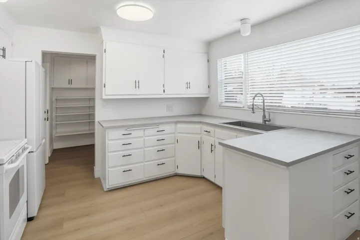 Kitchen featuring light countertops, white cabinets, light wood finished floors, white electric stove, and a peninsula