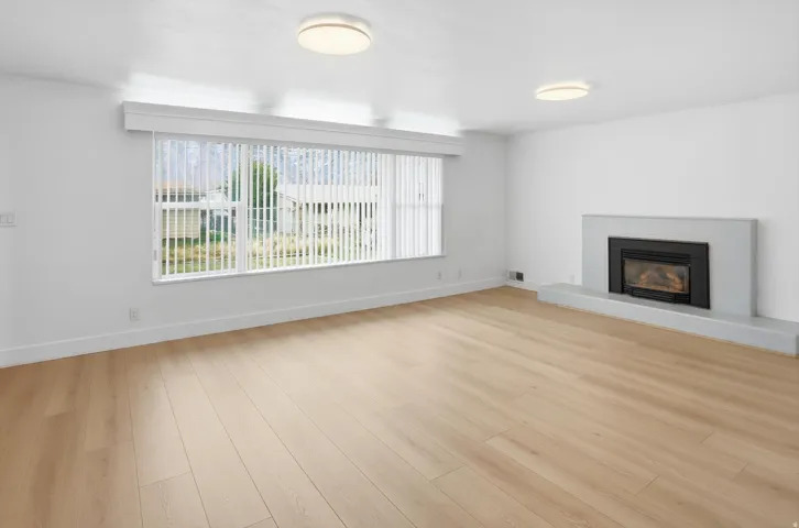 Unfurnished living room featuring a fireplace with raised hearth and light wood-style floors