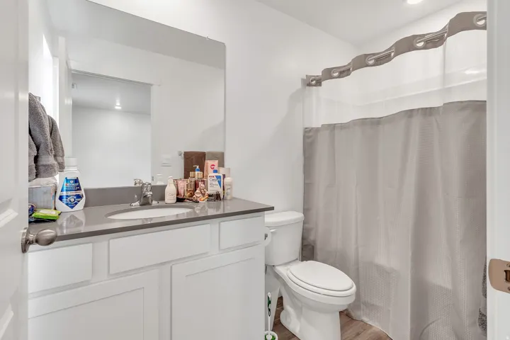 Bathroom featuring curtained shower, vanity, and light wood-style floors