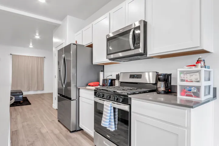 Kitchen with stainless steel appliances, white cabinets, light wood-type flooring, and recessed lighting
