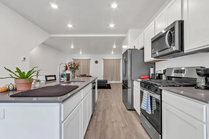 Kitchen with stainless steel appliances, white cabinetry, and dark stone counters