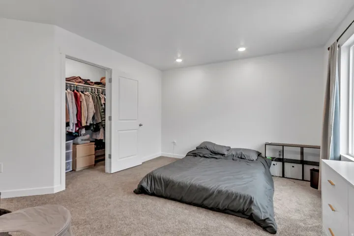 Bedroom featuring light carpet, a walk in closet, and recessed lighting