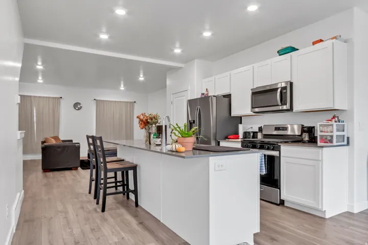 Kitchen featuring appliances with stainless steel finishes, a breakfast bar area, an island with sink, white cabinets, and light wood finished floors