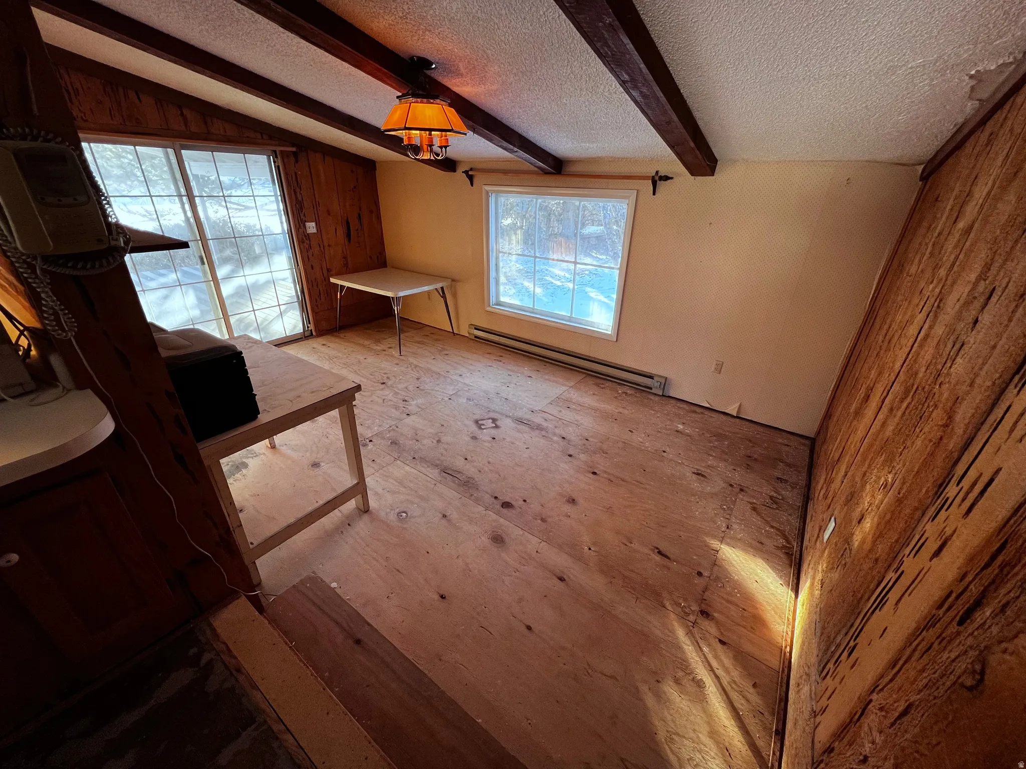 Unfurnished living room with a baseboard radiator, beamed ceiling, and a textured ceiling
