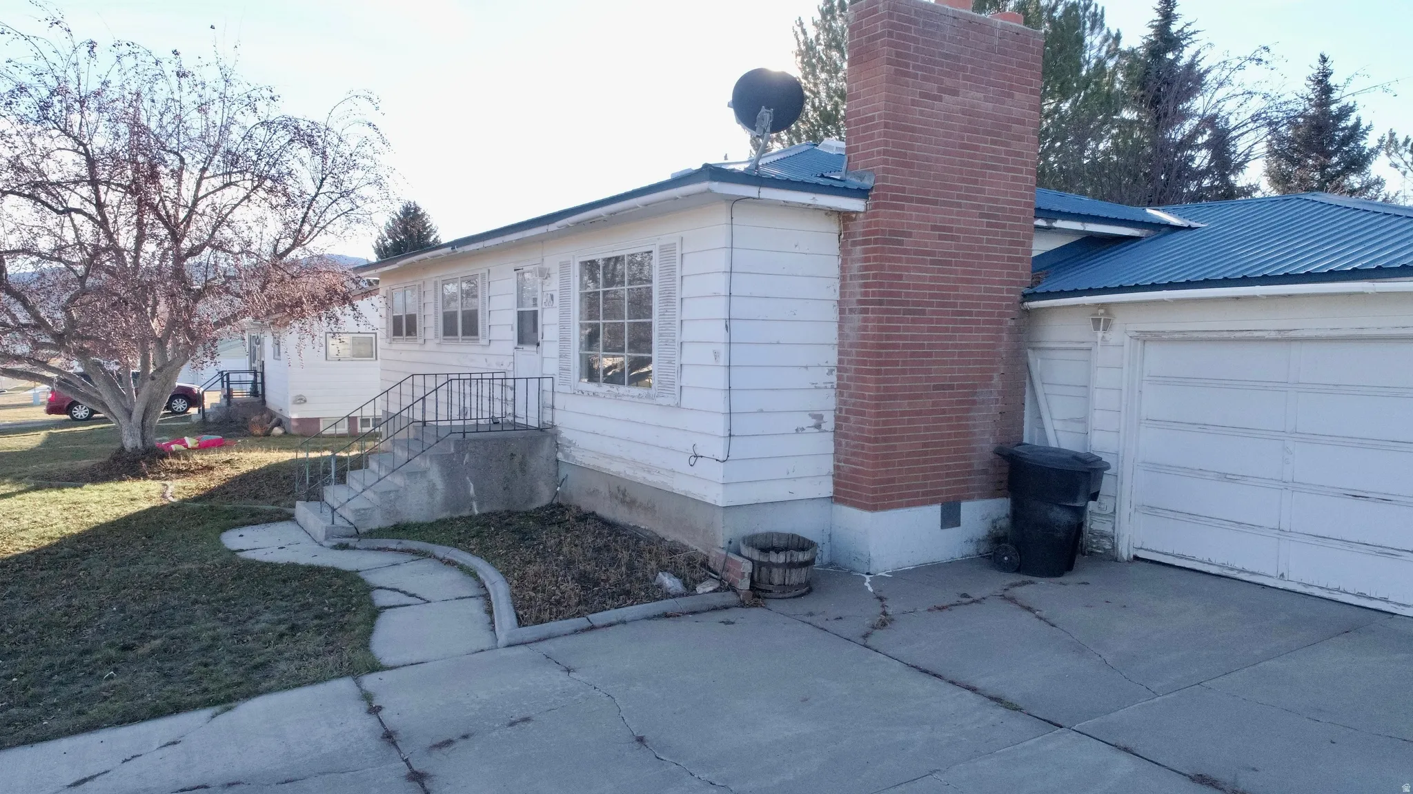 View of home's exterior with crawl space, a chimney, a metal roof, an attached garage, and a lawn