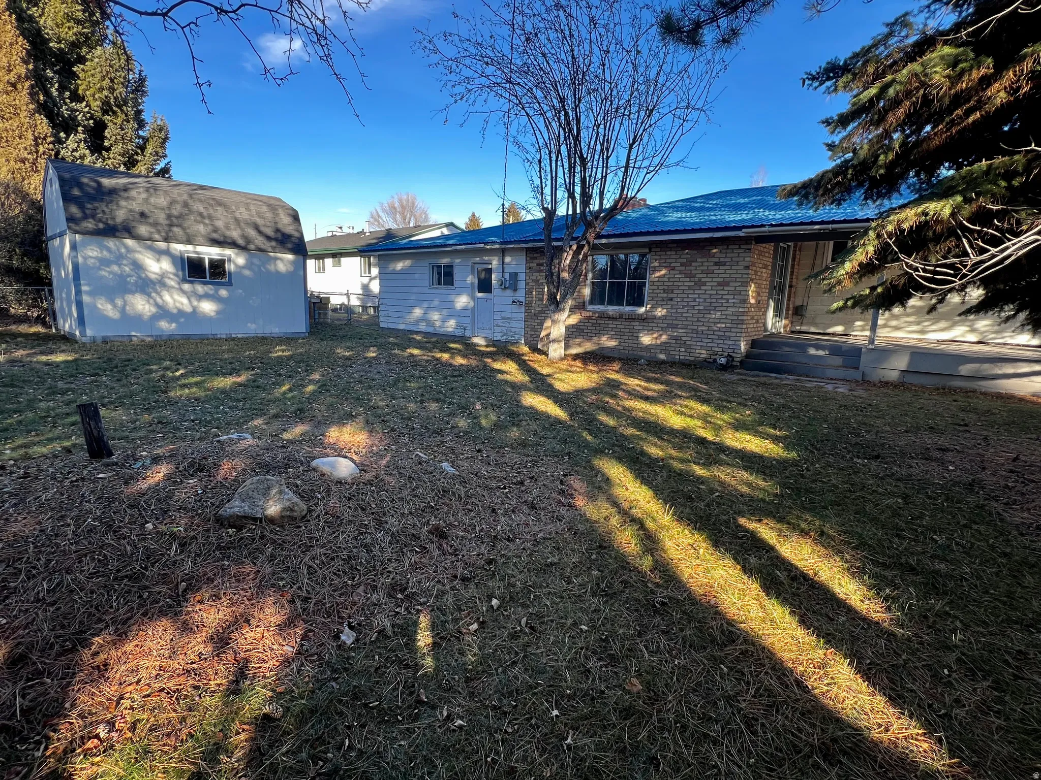 Rear view of property with an outbuilding, brick siding, and a yard