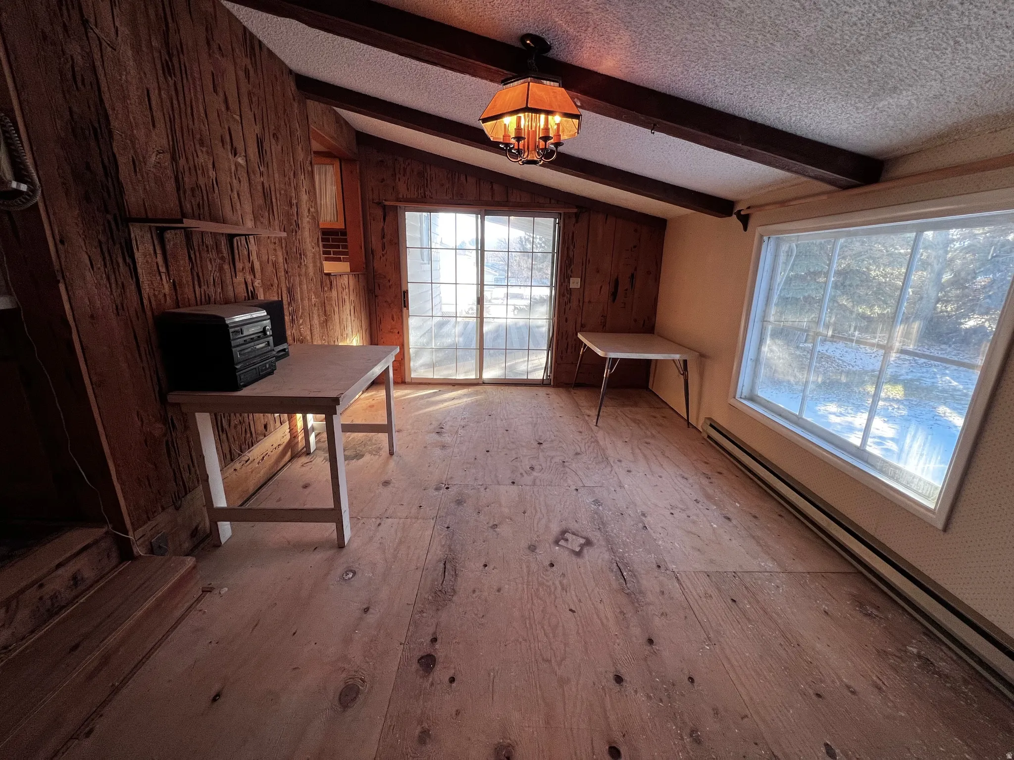 Unfurnished office with wooden walls, a baseboard heating unit, a chandelier, and a textured ceiling