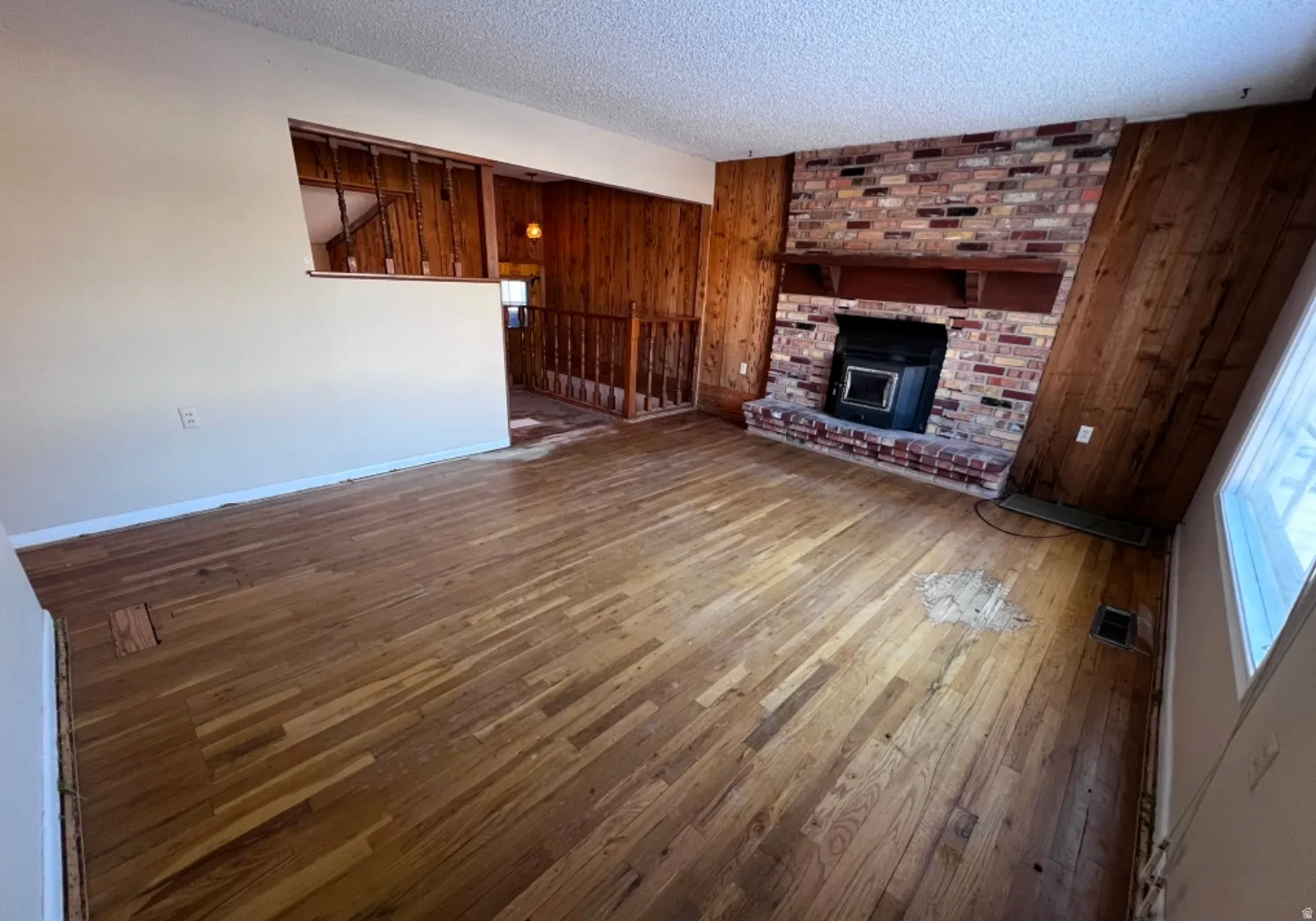 Unfurnished living room featuring hardwood / wood-style floors, wood walls, and a textured ceiling