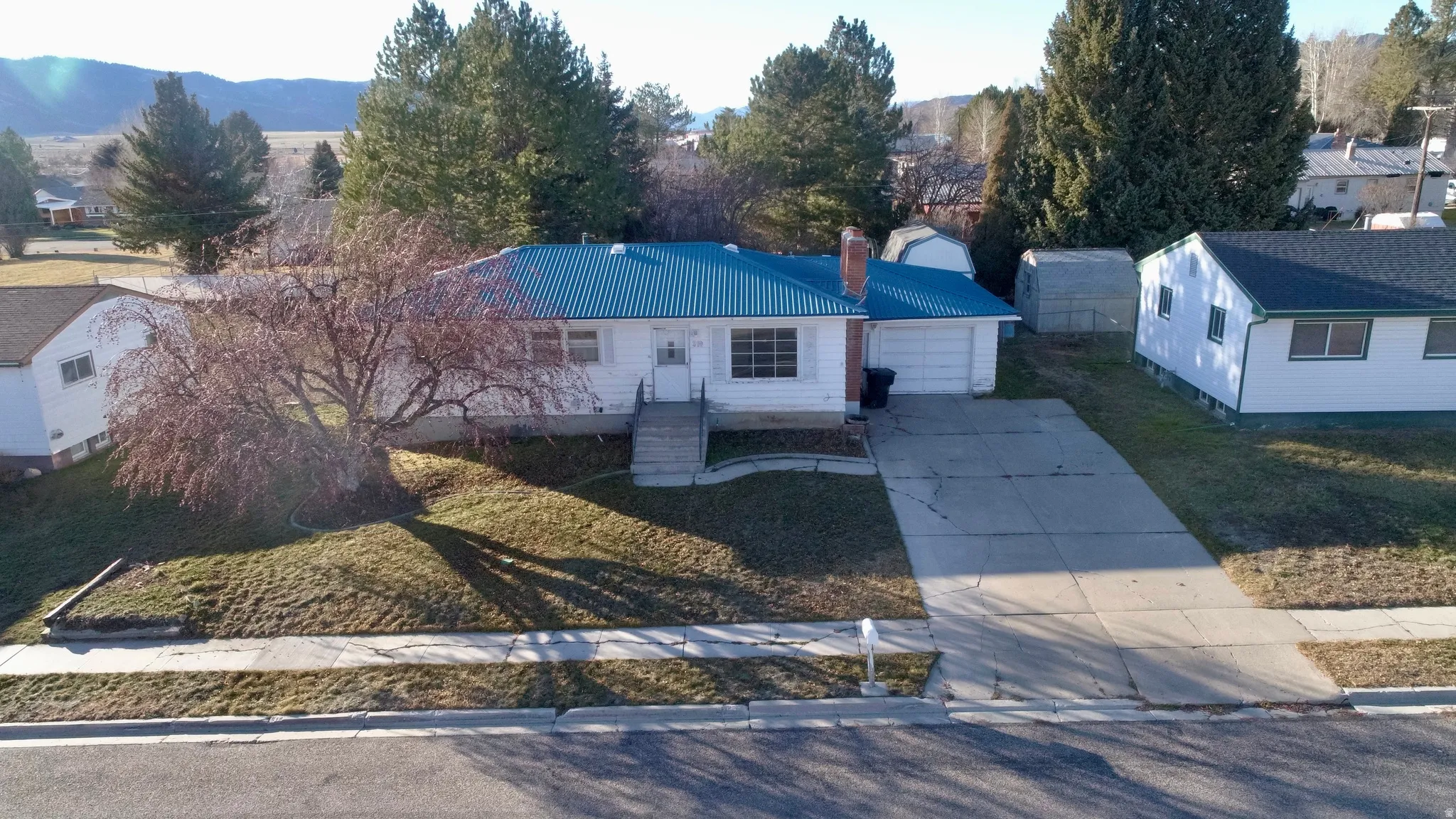 View of front facade featuring a metal roof, concrete driveway, a chimney, and a front yard