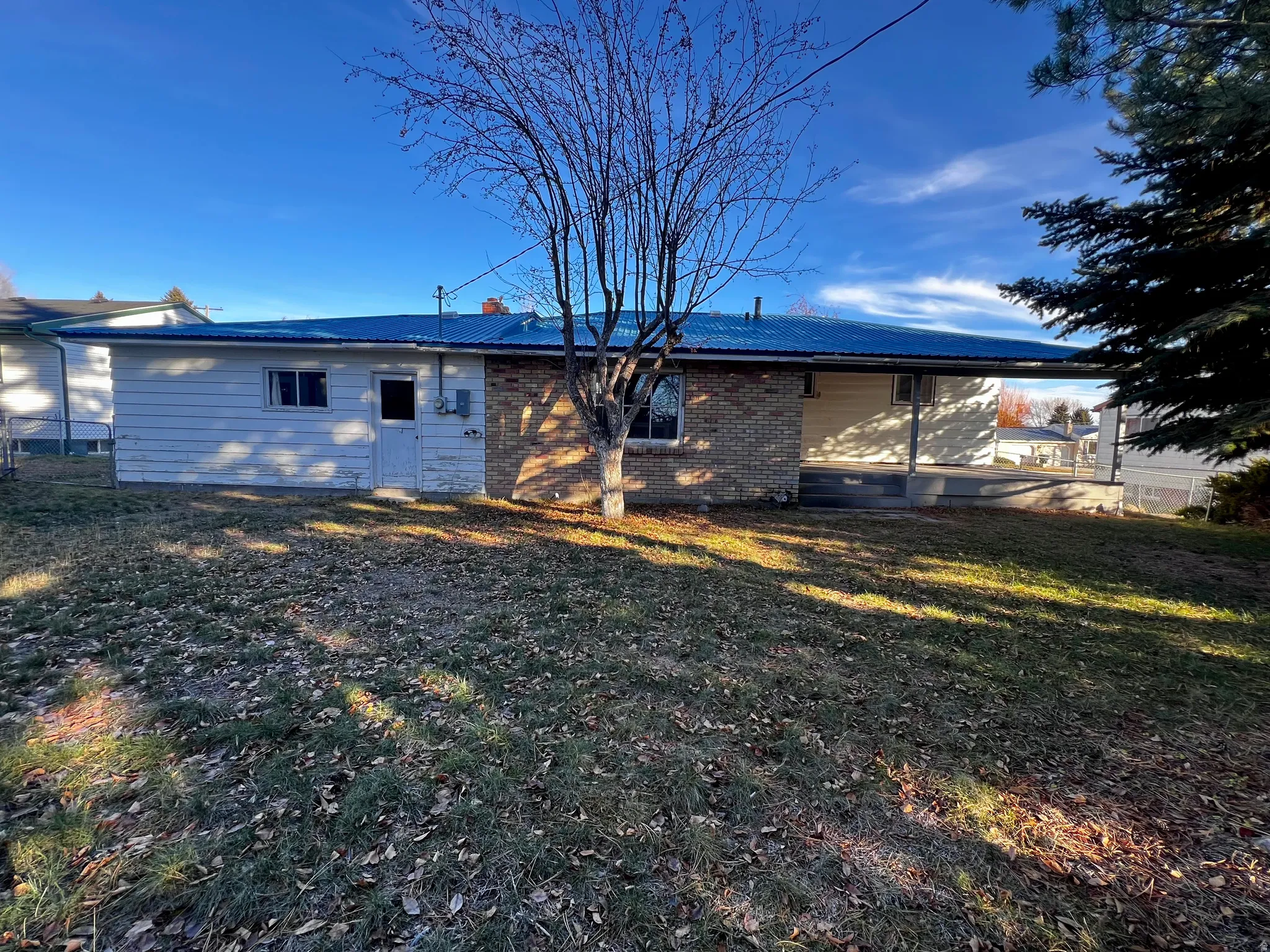 Rear view of property with a metal roof, brick siding, and a yard