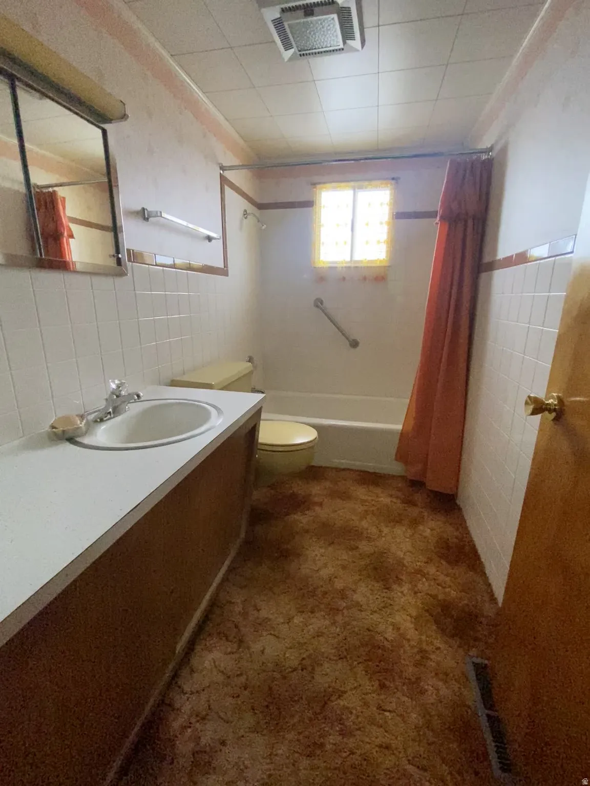 Full bath with tile walls, a wainscoted wall, shower / bath combo, and vanity