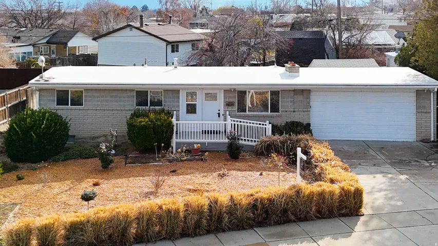 View of front of property with a chimney, brick siding, concrete driveway, a garage, and a residential view