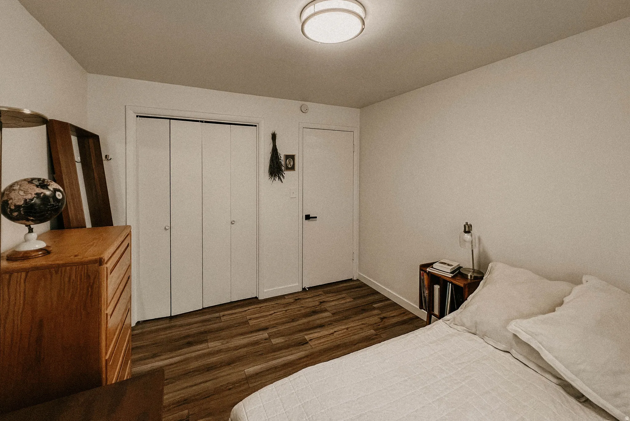 Bedroom with dark wood-style floors and a closet