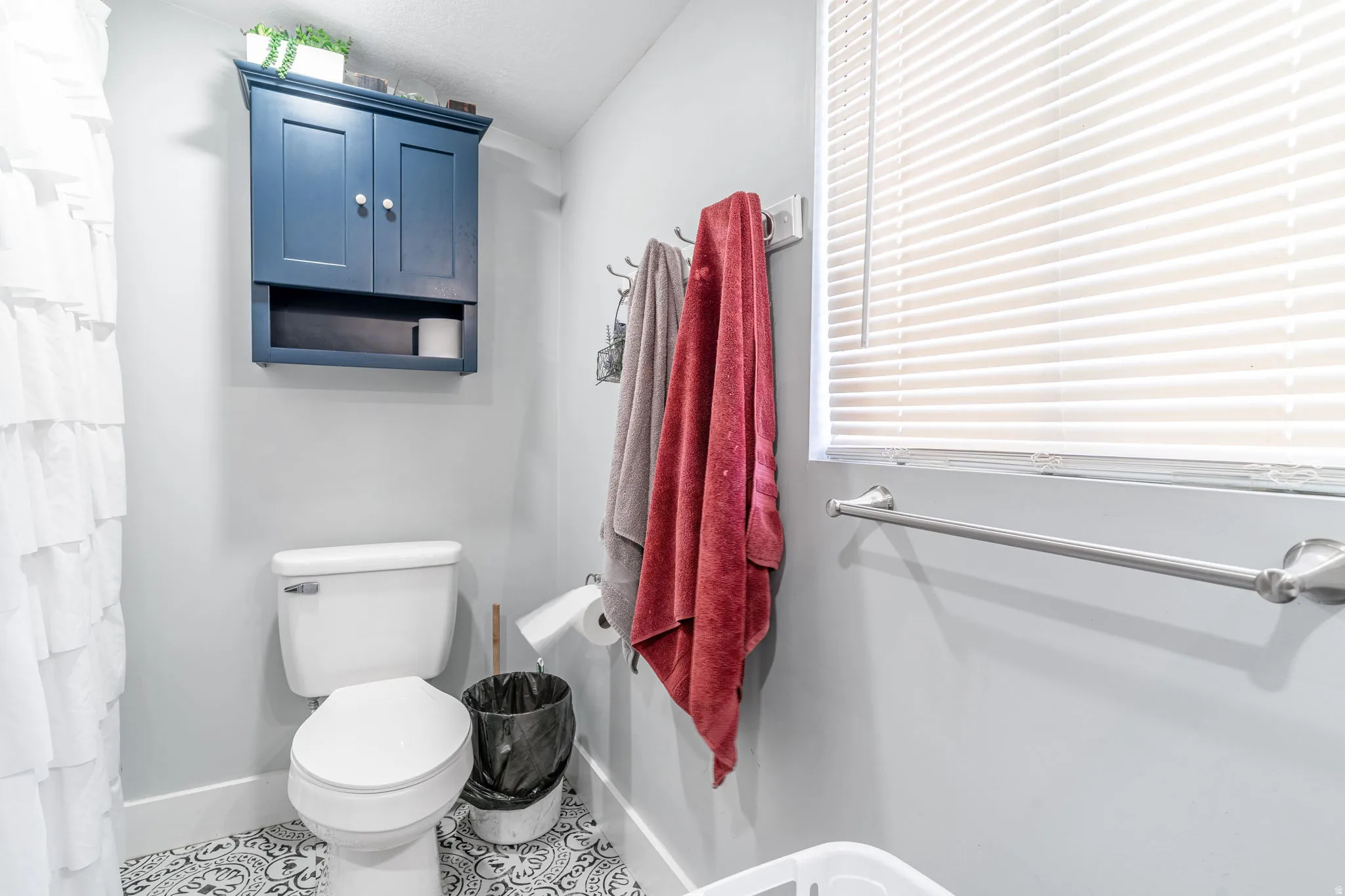 Bathroom with a shower with curtain and tile patterned flooring