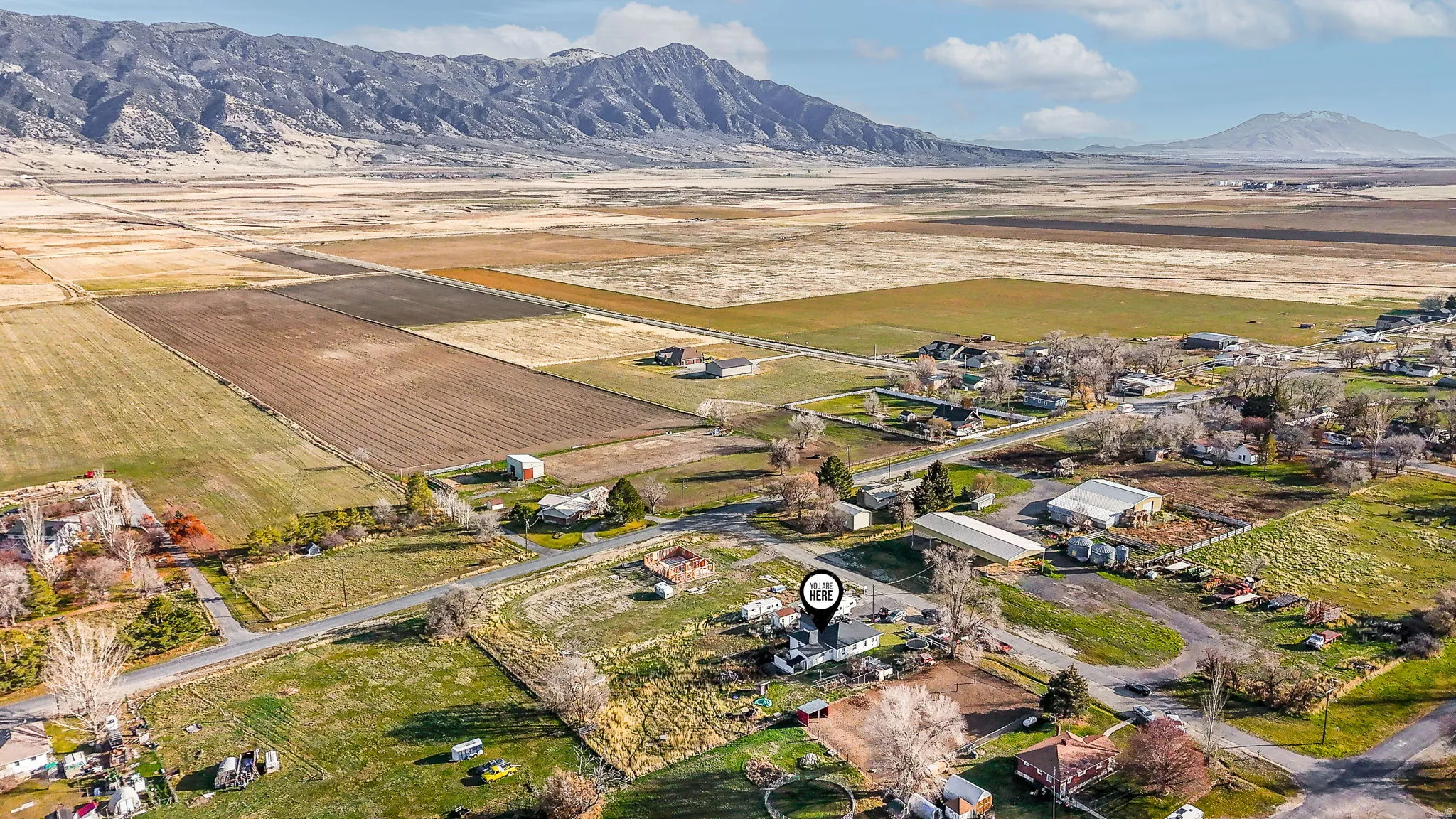 Aerial view of property's location with rural landscape, rows of crops, and a mountain backdrop