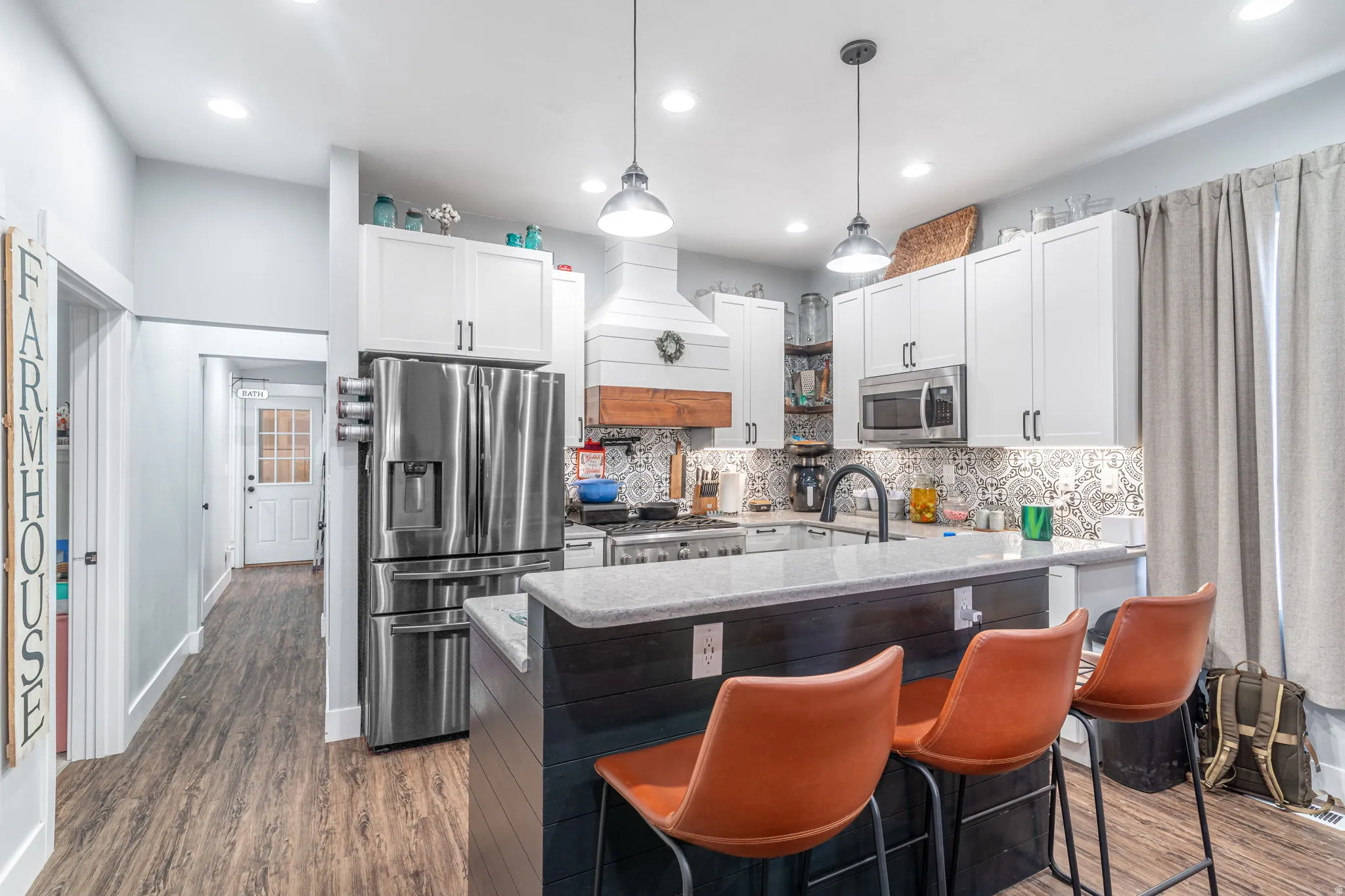 Kitchen featuring white cabinetry, stainless steel appliances, pendant lighting, light stone countertops, and recessed lighting