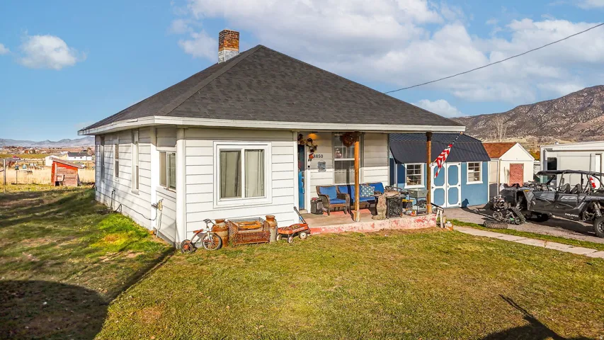 Rear view of property featuring a mountain view, a lawn, a chimney, and a shingled roof