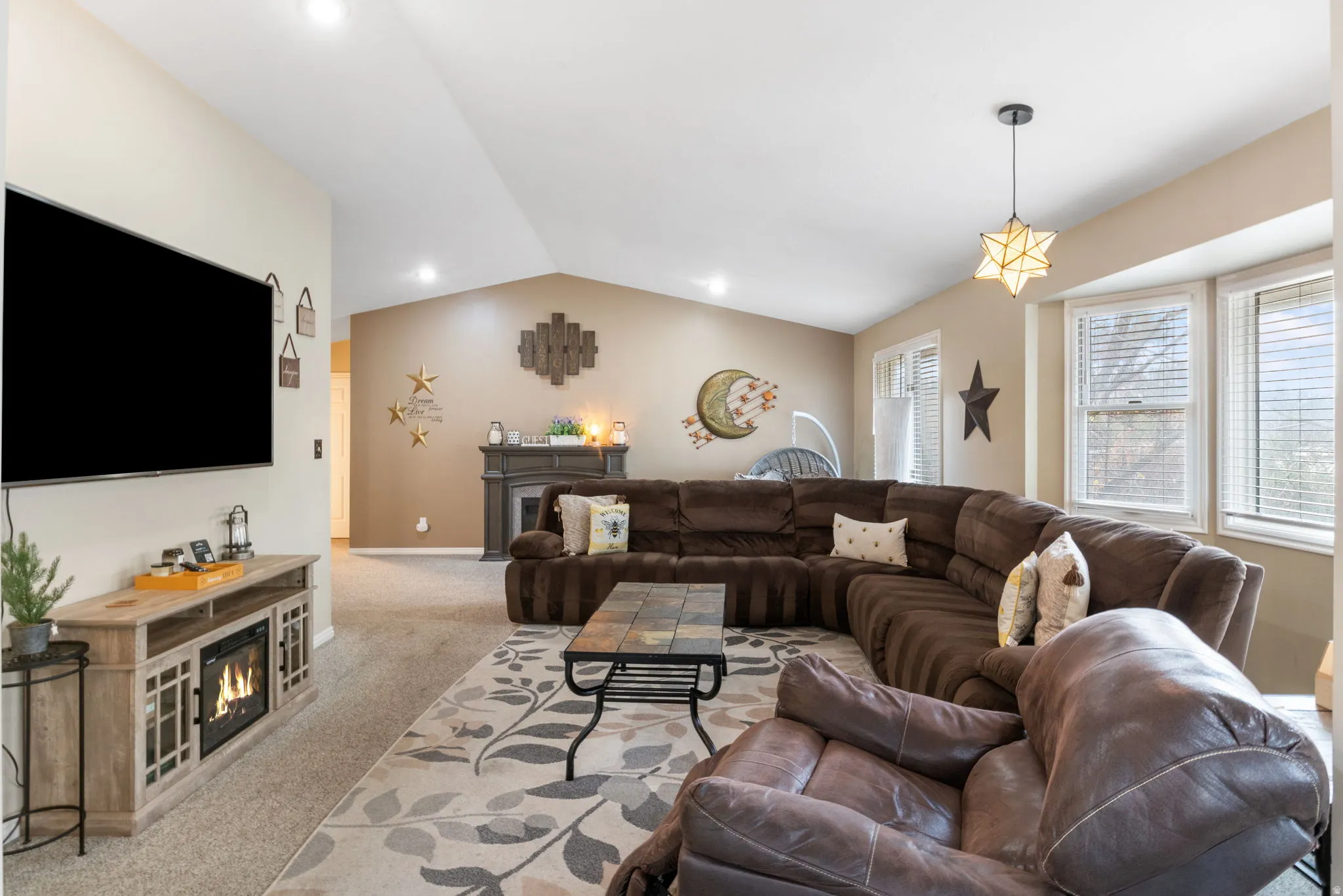Living room featuring lofted ceiling, light colored carpet, and a glass covered fireplace
