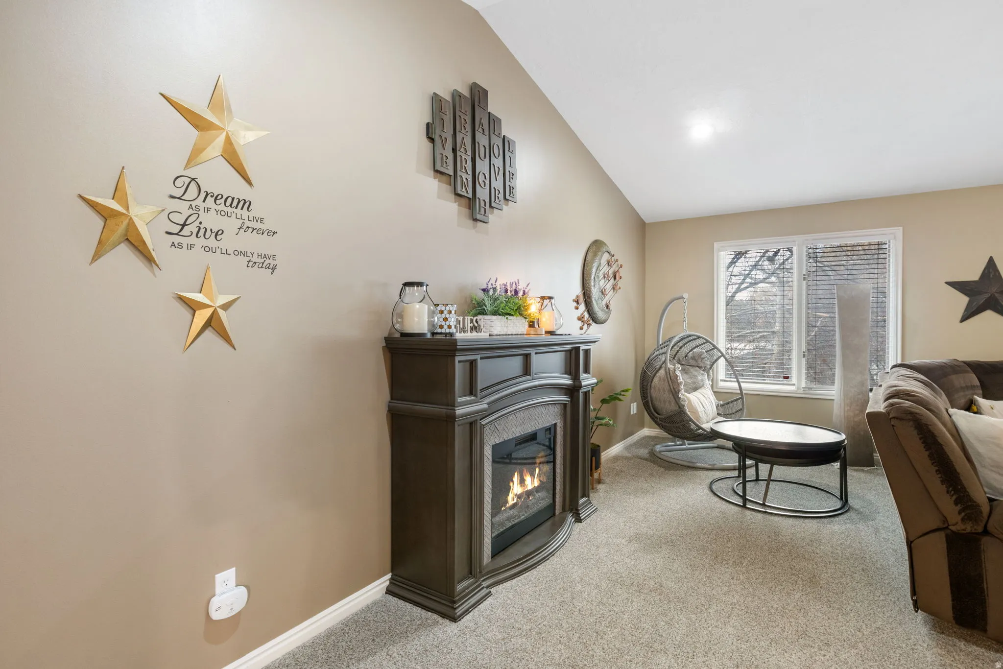 Carpeted living area with vaulted ceiling and a glass covered fireplace