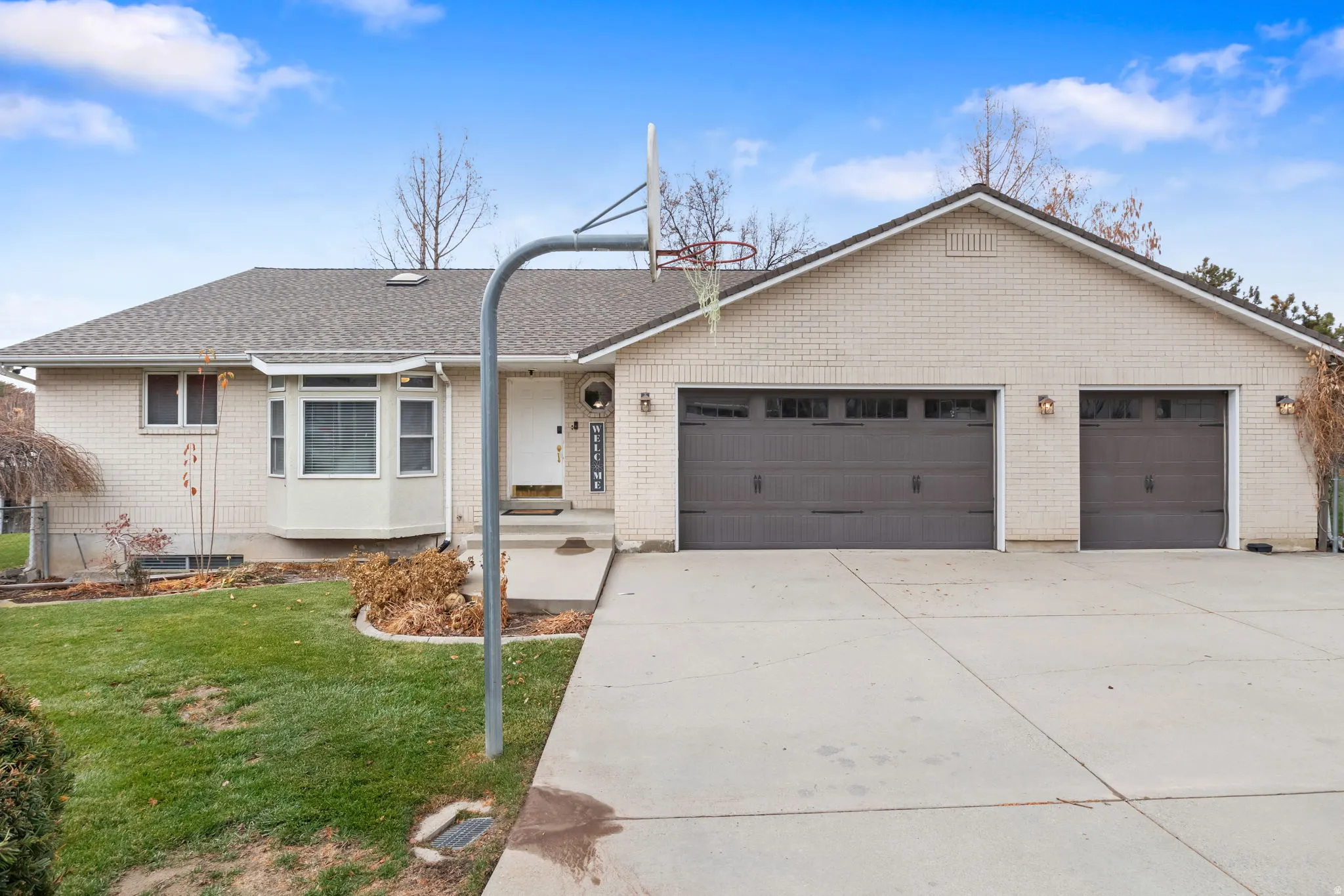 Single story home with concrete driveway, a garage, roof with shingles, a front lawn, and brick siding
